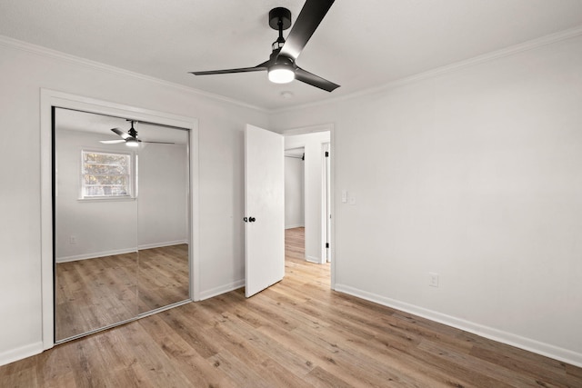 unfurnished bedroom featuring ceiling fan, light wood-type flooring, crown molding, and a closet