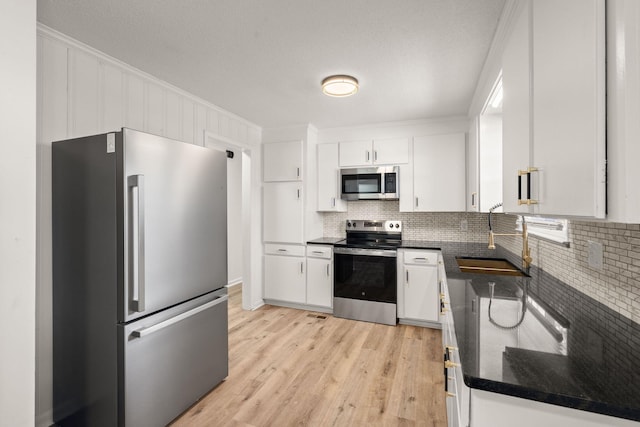 kitchen featuring white cabinetry, sink, tasteful backsplash, light hardwood / wood-style flooring, and appliances with stainless steel finishes