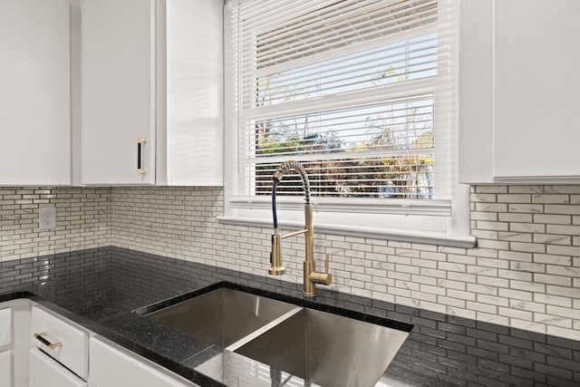 kitchen with white cabinetry, dark stone counters, and sink