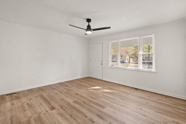 spare room with a textured ceiling, ceiling fan, light wood-type flooring, and ornamental molding