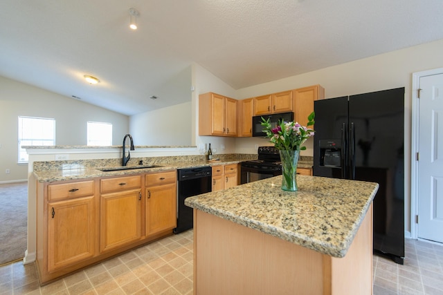 kitchen featuring black appliances, a kitchen island, light stone counters, and a sink