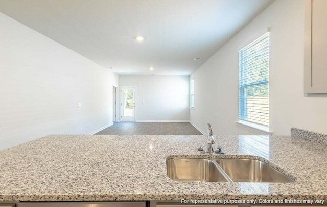 kitchen featuring light stone countertops, open floor plan, and a sink