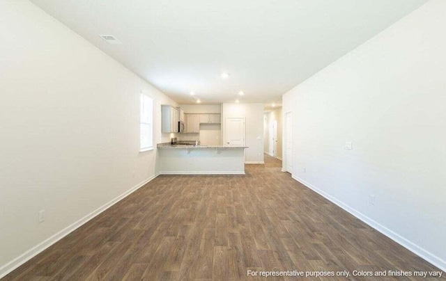 unfurnished living room with dark wood finished floors, visible vents, and baseboards