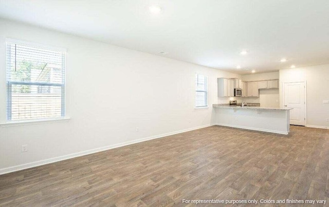 unfurnished living room featuring recessed lighting, wood finished floors, and baseboards