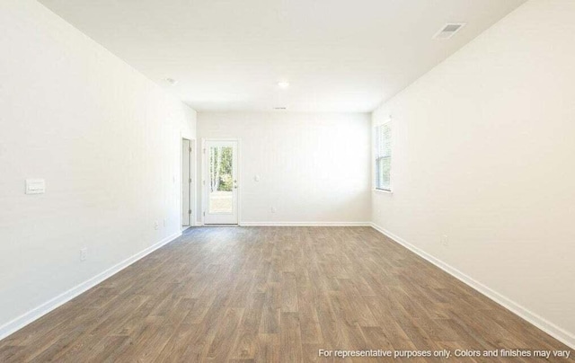 unfurnished room featuring visible vents, baseboards, and wood finished floors