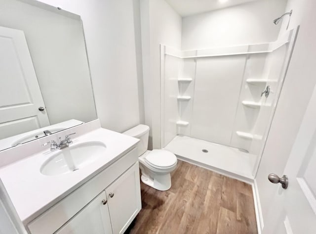 full bathroom featuring a stall shower, toilet, wood finished floors, and vanity