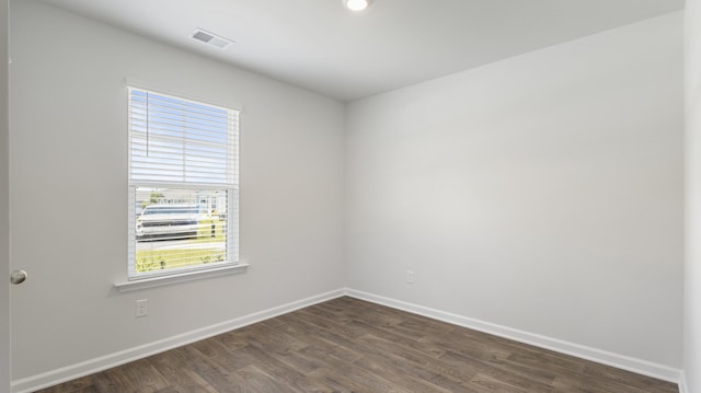 empty room with visible vents, dark wood-type flooring, and baseboards