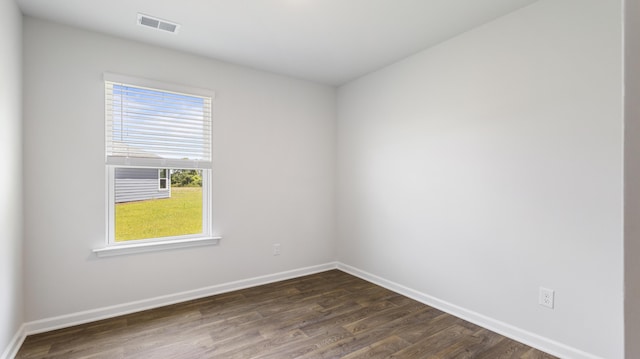 unfurnished room with dark wood-style floors, visible vents, and baseboards