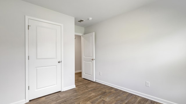 unfurnished bedroom featuring visible vents, dark wood-type flooring, and baseboards