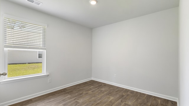 empty room with visible vents, baseboards, and dark wood-style flooring