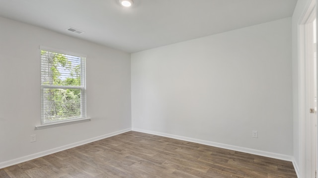 empty room featuring visible vents, baseboards, and wood finished floors