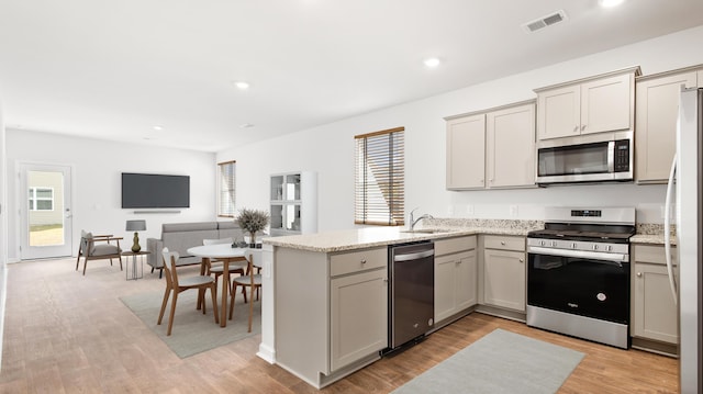 kitchen with visible vents, gray cabinets, a sink, stainless steel appliances, and a peninsula