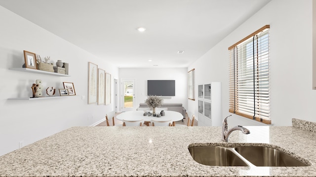 kitchen with recessed lighting, light stone countertops, and a sink