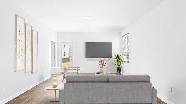 living room with visible vents, baseboards, and wood finished floors