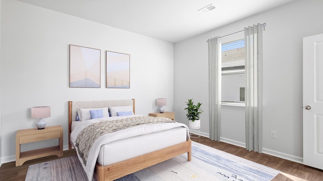 bedroom featuring visible vents, baseboards, and wood finished floors