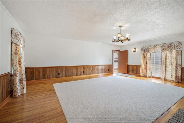 2830 Wire Rd, Saint George, SC 29477 - spare room with a textured ceiling, light hardwood / wood-style flooring, a chandelier, and wood walls