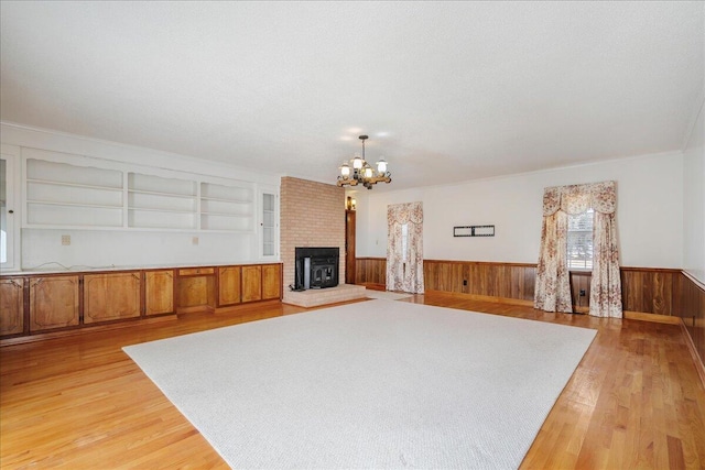 2830 Wire Rd, Saint George, SC 29477 - unfurnished living room with an inviting chandelier, wood walls, built in features, and light wood-type flooring