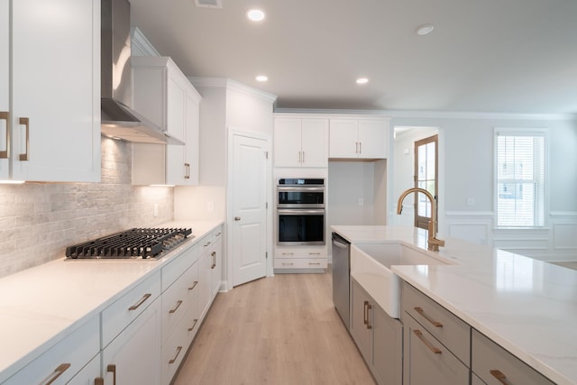 kitchen with white cabinets, sink, wall chimney exhaust hood, and appliances with stainless steel finishes