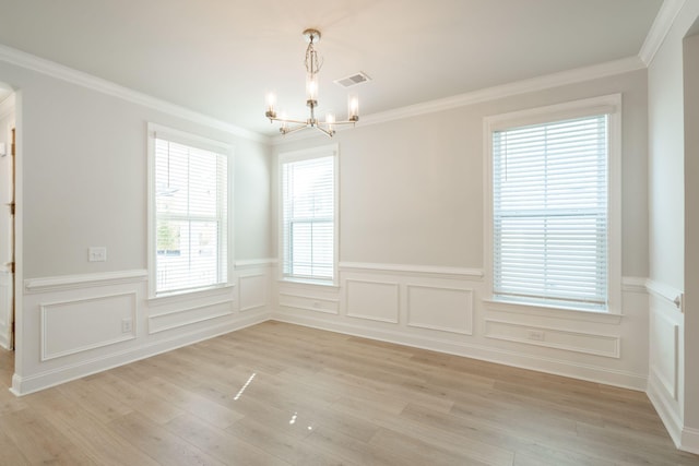 empty room featuring crown molding, a chandelier, and light wood-type flooring