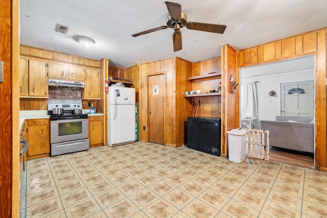 kitchen with ceiling fan, backsplash, white refrigerator, stainless steel electric stove, and wood walls