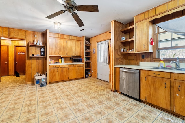 kitchen with ceiling fan, appliances with stainless steel finishes, sink, and wooden walls