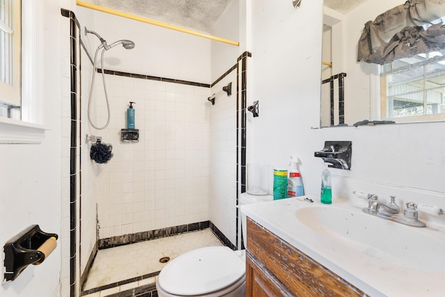 bathroom with vanity, toilet, and tiled shower