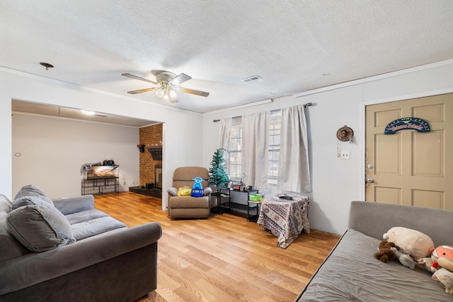 living room with ceiling fan, ornamental molding, light hardwood / wood-style floors, and a textured ceiling