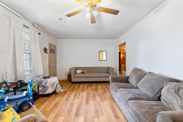 living room with ornamental molding, ceiling fan, and light hardwood / wood-style floors