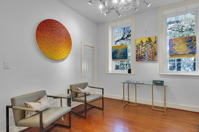 sitting room with an inviting chandelier, hardwood / wood-style flooring, rail lighting, and a wealth of natural light