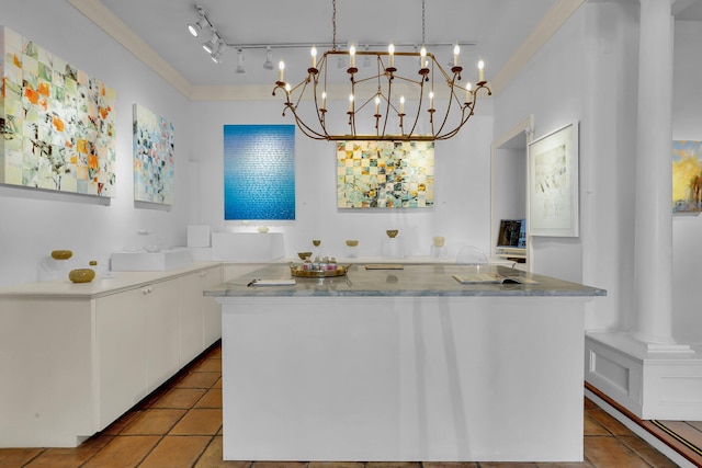 kitchen featuring white cabinets, decorative light fixtures, a center island, crown molding, and ornate columns