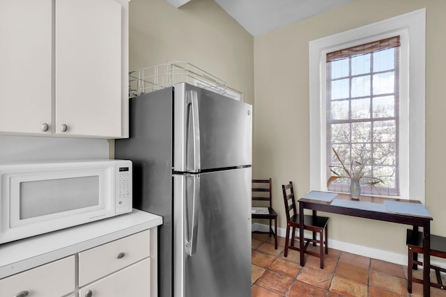 kitchen with stainless steel refrigerator and white cabinetry