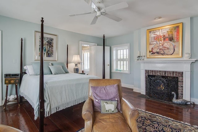 bedroom featuring dark wood-type flooring, a brick fireplace, and ceiling fan