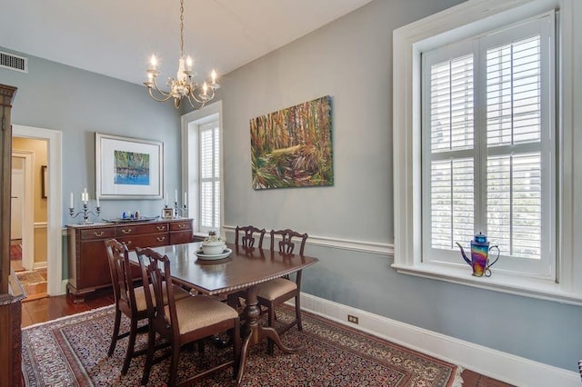 dining room with dark hardwood / wood-style floors and a chandelier