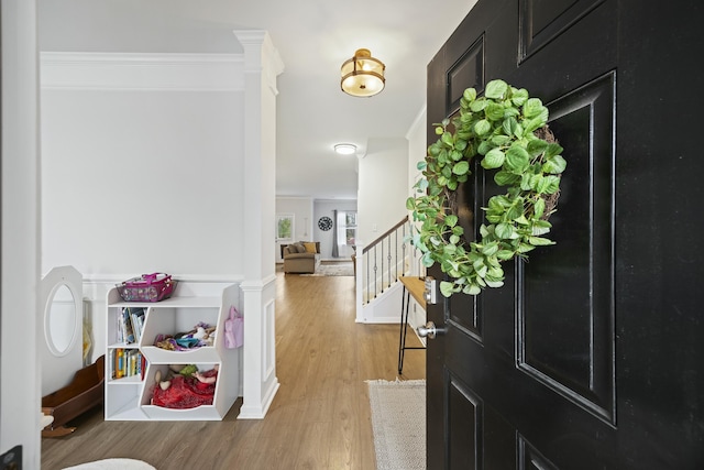 entryway with ornamental molding and light hardwood / wood-style floors