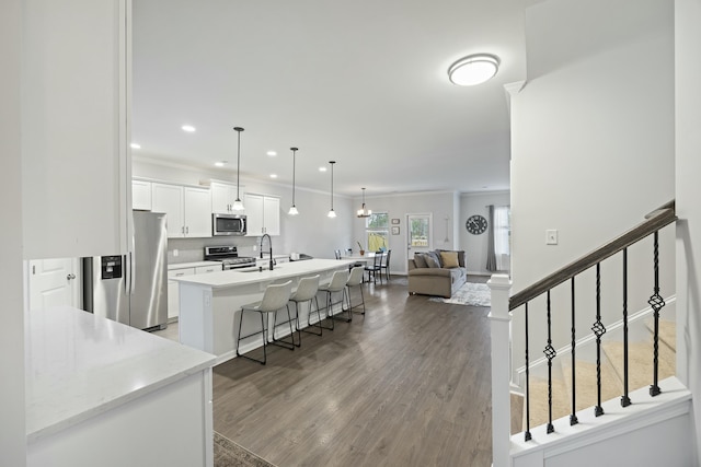 kitchen with appliances with stainless steel finishes, a breakfast bar, decorative light fixtures, white cabinetry, and a center island