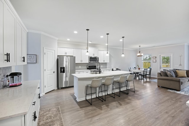 kitchen with sink, decorative light fixtures, appliances with stainless steel finishes, an island with sink, and white cabinets