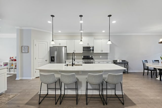 kitchen featuring white cabinetry, sink, stainless steel appliances, and an island with sink