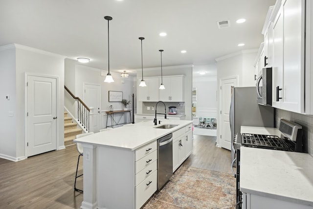 kitchen featuring appliances with stainless steel finishes, sink, a center island with sink, and white cabinets