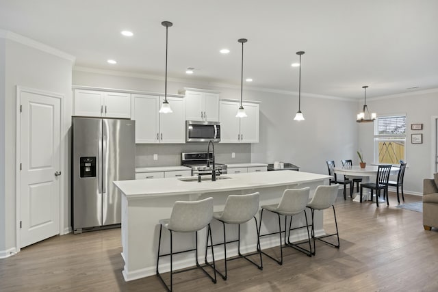 kitchen featuring hanging light fixtures, an island with sink, appliances with stainless steel finishes, and white cabinetry