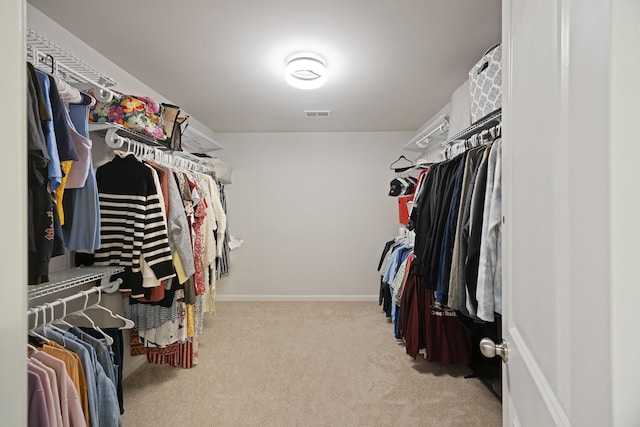 walk in closet with light carpet