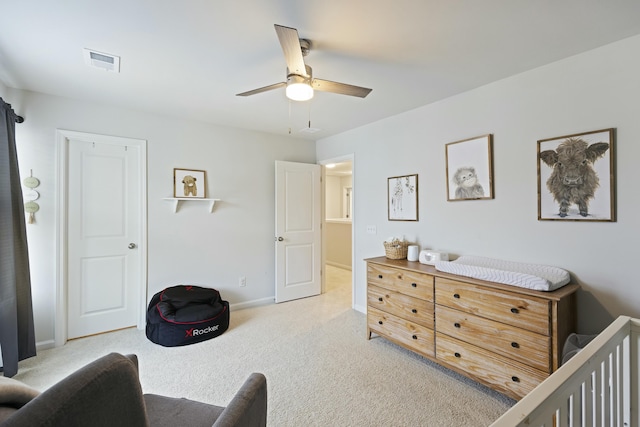 carpeted bedroom featuring a nursery area and ceiling fan