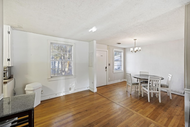 dining space with hardwood / wood-style floors, a textured ceiling, and an inviting chandelier