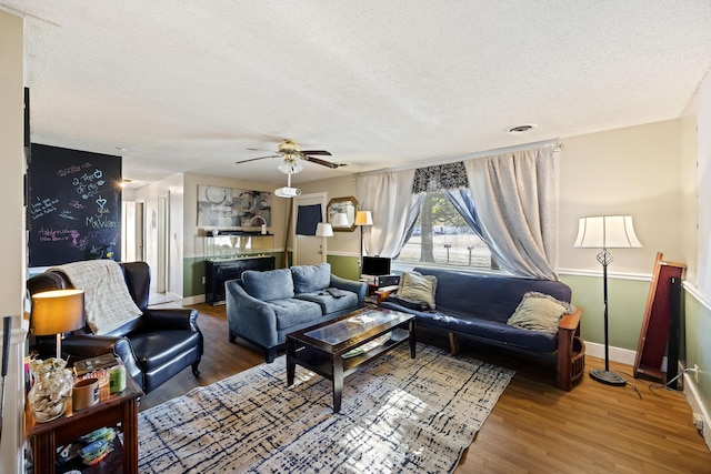 living room featuring ceiling fan, hardwood / wood-style floors, and a textured ceiling