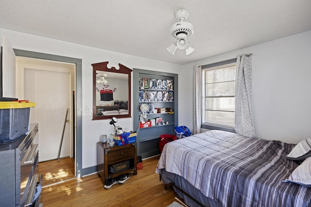 bedroom with ceiling fan, wood-type flooring, and a textured ceiling