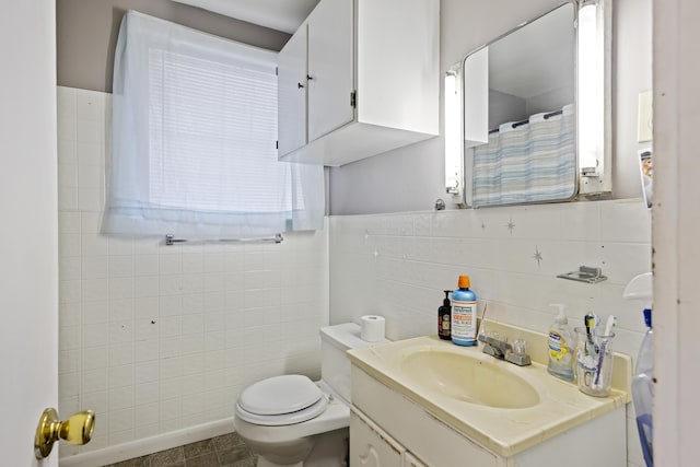 bathroom featuring tile patterned floors, vanity, toilet, and tile walls