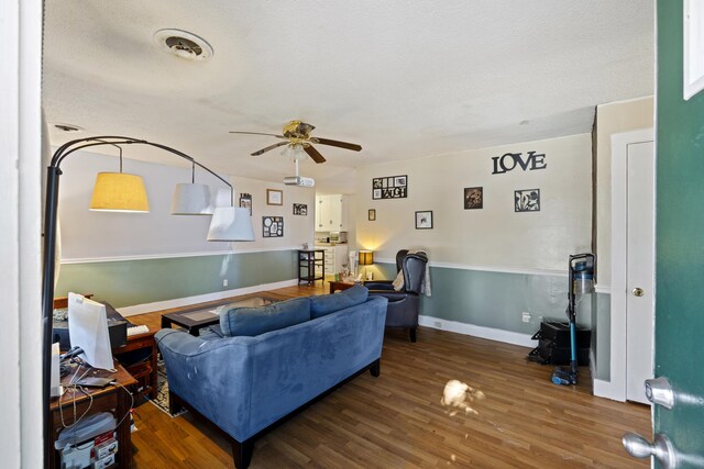 living room featuring a textured ceiling, ceiling fan, and dark wood-type flooring