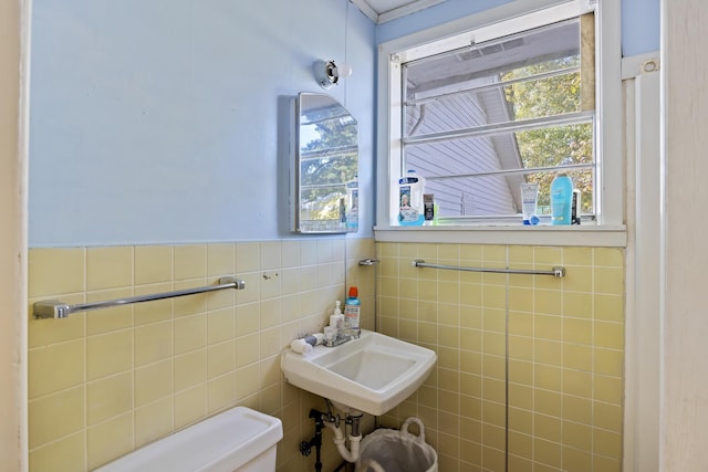 bathroom featuring toilet, tile walls, and sink