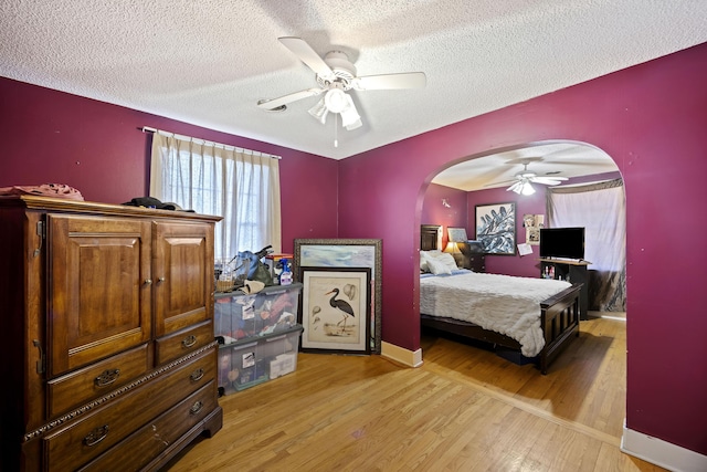 bedroom featuring ceiling fan, light hardwood / wood-style flooring, and a textured ceiling