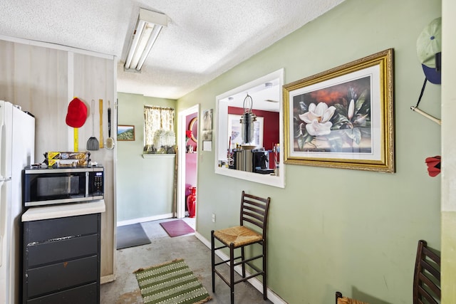 interior space with a breakfast bar, a textured ceiling, light colored carpet, and white refrigerator