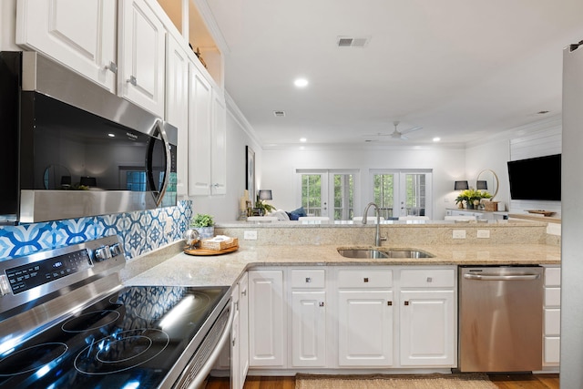 kitchen with a sink, appliances with stainless steel finishes, white cabinets, and a ceiling fan